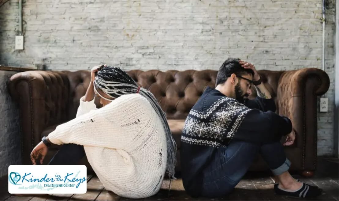 A sad couple sitting back to back, looking distressed, symbolizing codependency and emotional struggle.