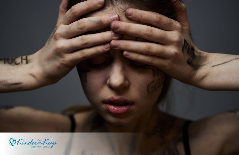 A woman covering her head and eyes looking emotionally drained from abuse of a narcissist 