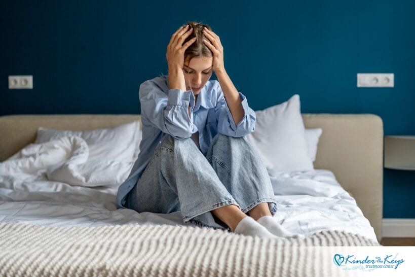 Woman curled up holding her head, showing emotional distress from complex PTSD