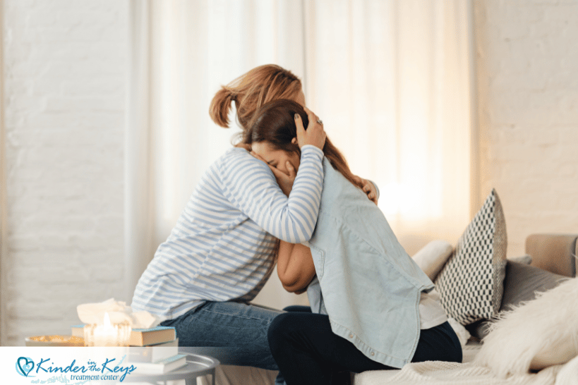 Family comforting and hugging a woman crying, showing emotional support in recovery