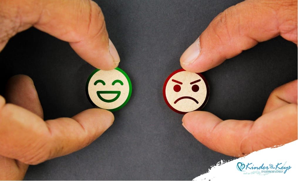 Two hands holding a smiling face and an angry face representing the hidden emotional contrast of high-functioning depression