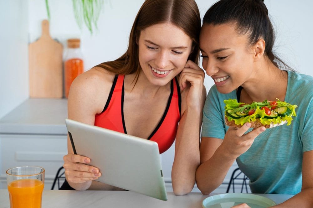 Two women reviewing Kinder in the Keys new healthy meal plan options on a tablet.