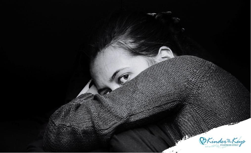 Woman resting her head on her arms showing signs of high-functioning depression