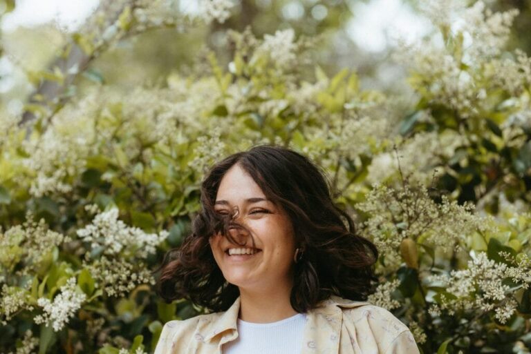 Woman smiling peacefully surrounded by spring plants
